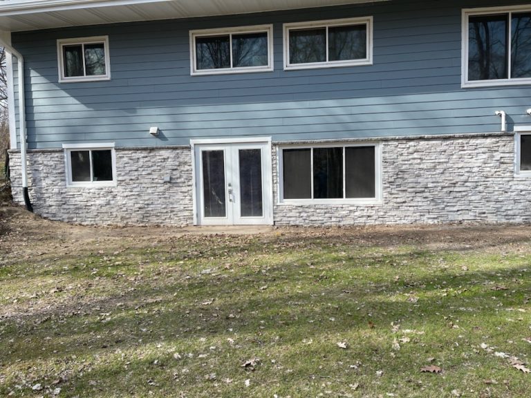 Lower level of a two-story home finished in light stone veneer