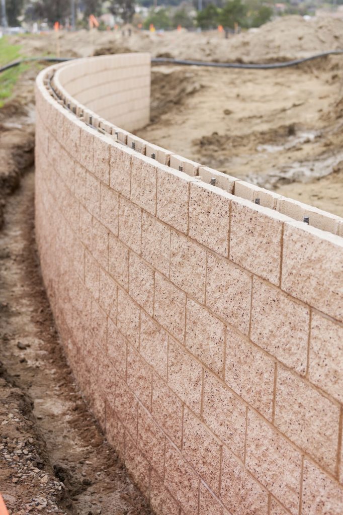 Curved segmental retaining wall being built on a sloped residential lot