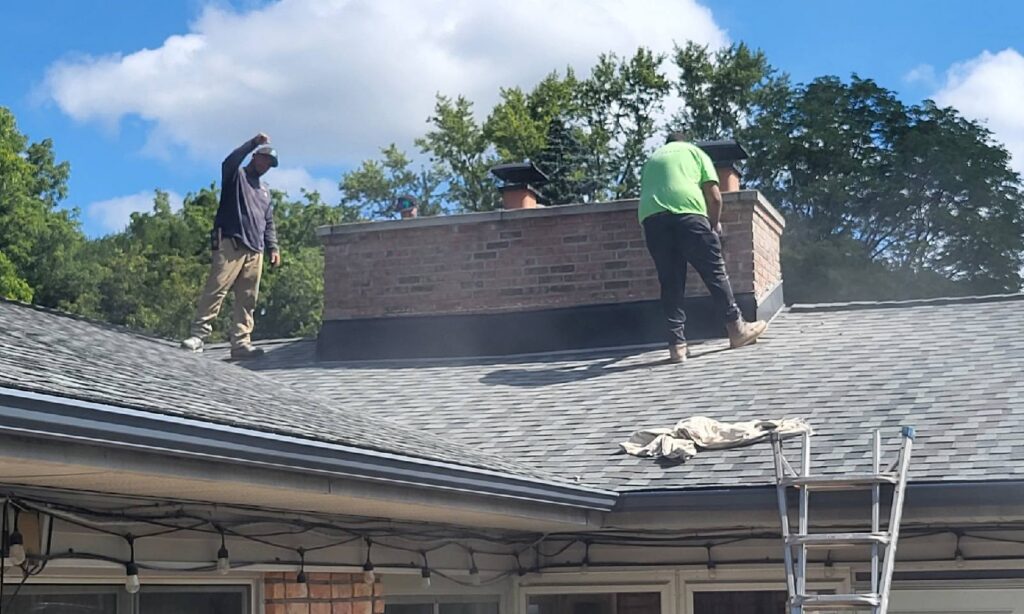 Masonry crew rebuilding a brick chimney on a residential roof
